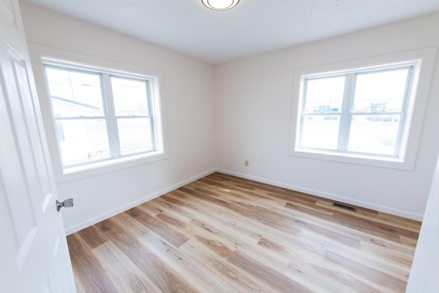 empty room featuring visible vents, baseboards, and light wood-style flooring