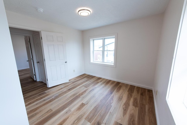 unfurnished bedroom featuring light wood-type flooring and baseboards