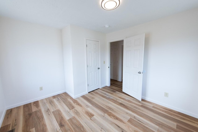 unfurnished bedroom with a closet, baseboards, and light wood-style flooring