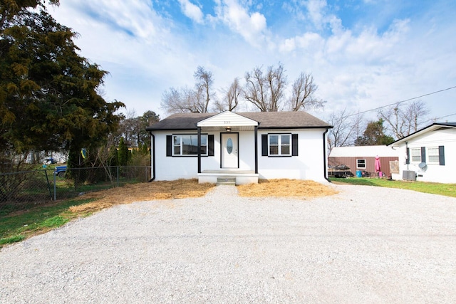 bungalow-style house featuring central AC, a shingled roof, driveway, and fence