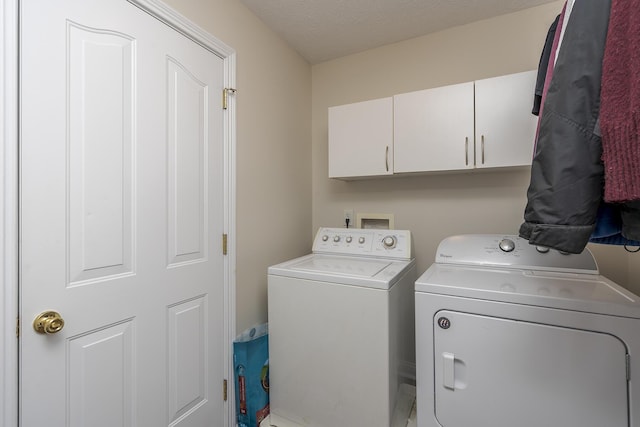 laundry room featuring separate washer and dryer, a textured ceiling, and cabinets