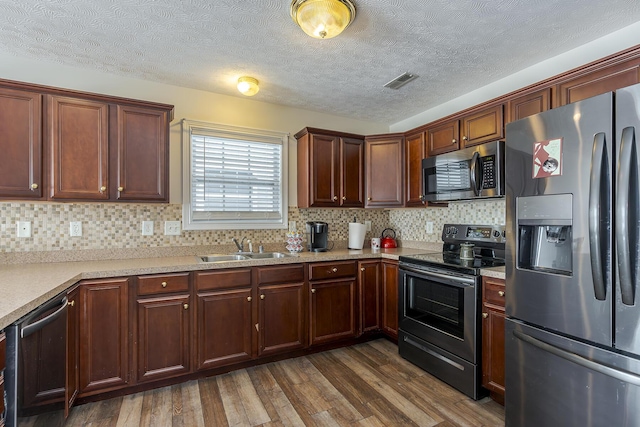 kitchen with dark wood-type flooring, sink, appliances with stainless steel finishes, and tasteful backsplash