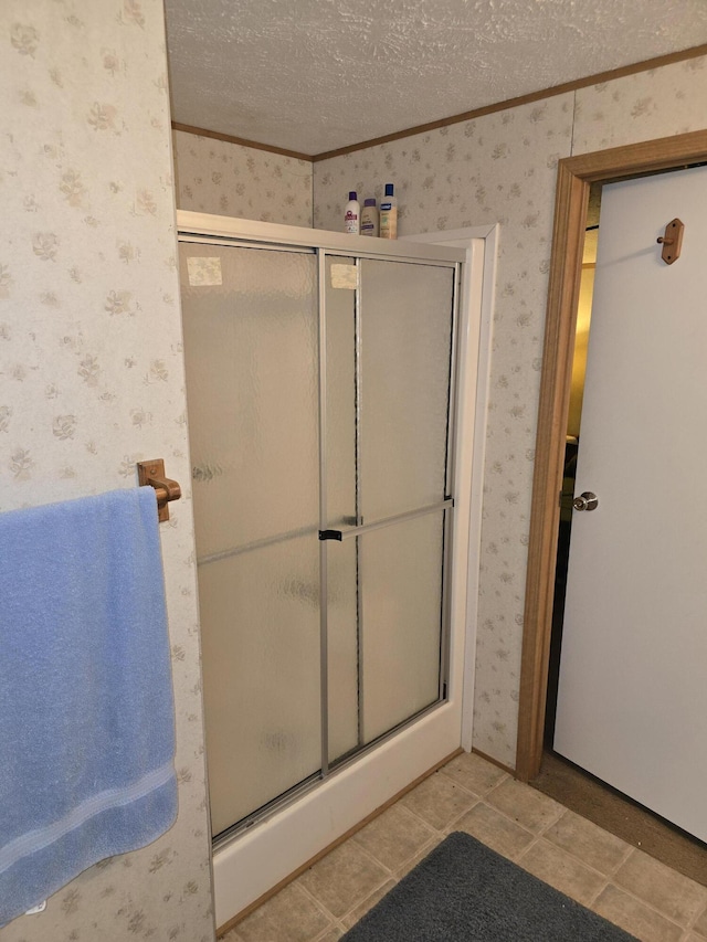 bathroom with a textured ceiling, a shower with door, crown molding, and tile patterned flooring