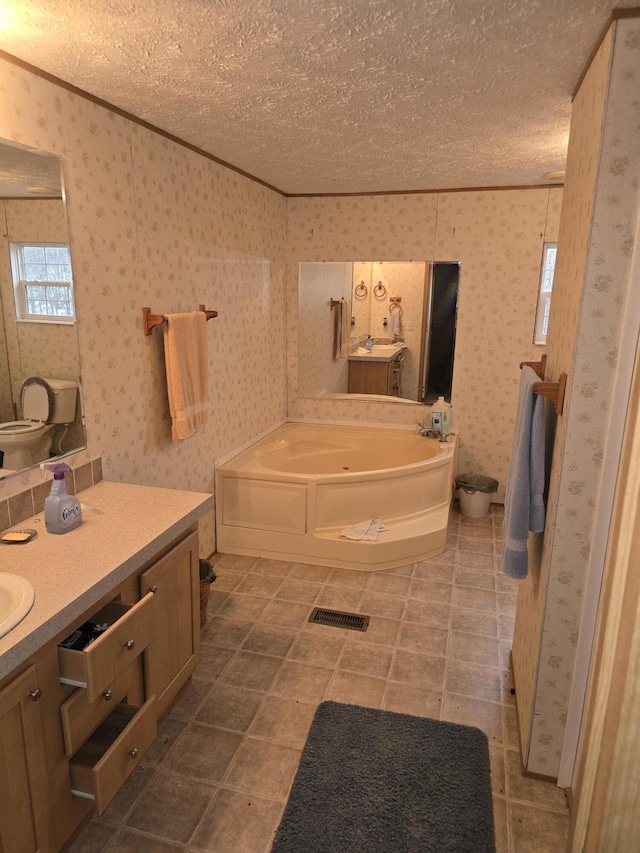 bathroom with a textured ceiling, a tub to relax in, and vanity