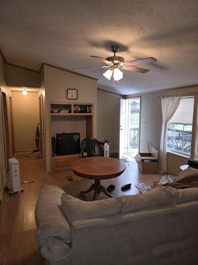 living room with a textured ceiling, ceiling fan, a wealth of natural light, and ornamental molding