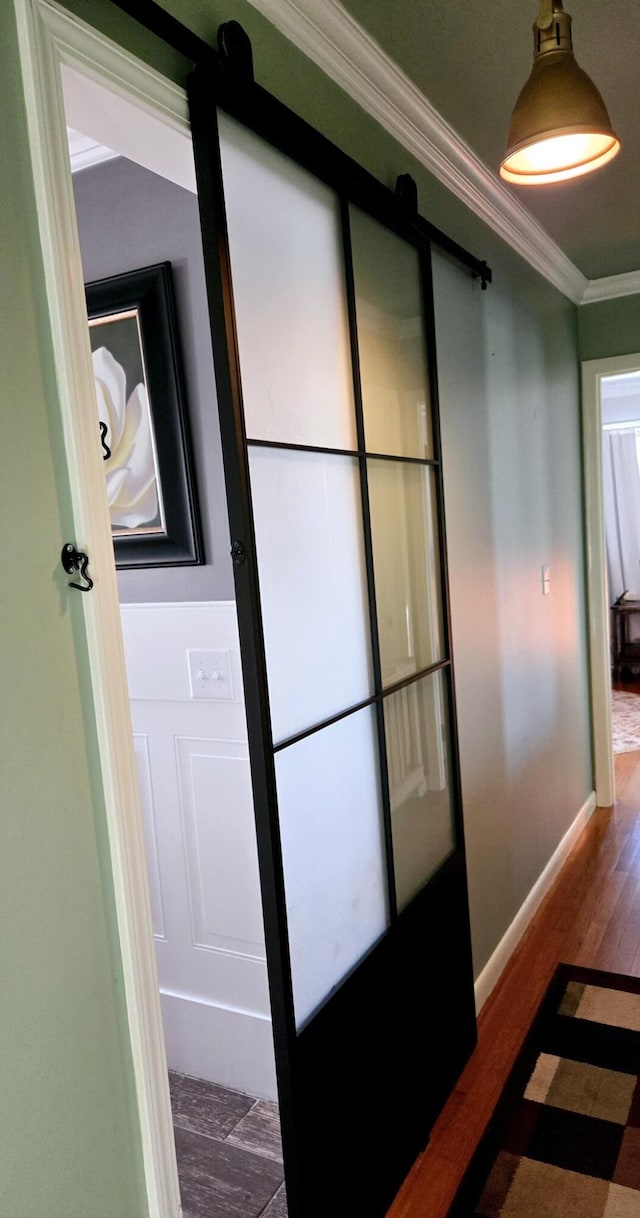 hallway featuring crown molding, dark hardwood / wood-style floors, and a barn door