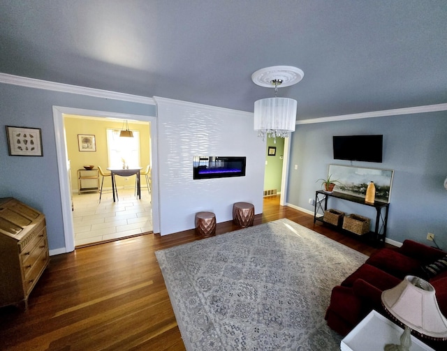 living room with dark hardwood / wood-style flooring, a notable chandelier, and crown molding