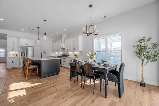 dining space featuring sink, a chandelier, and light wood-type flooring