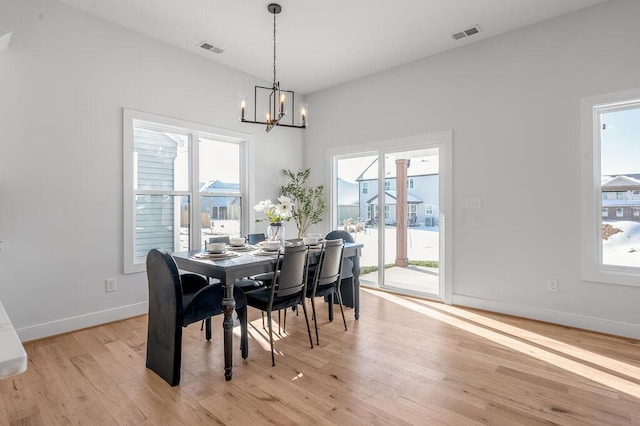 dining room with a healthy amount of sunlight, an inviting chandelier, and light hardwood / wood-style flooring