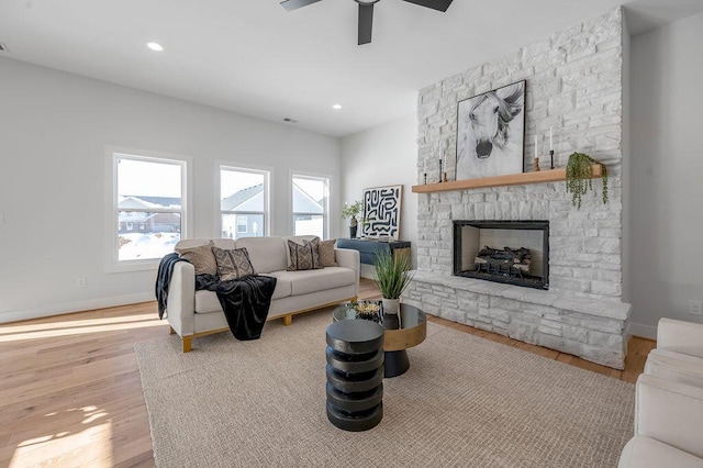 living room with ceiling fan, light hardwood / wood-style flooring, and a fireplace