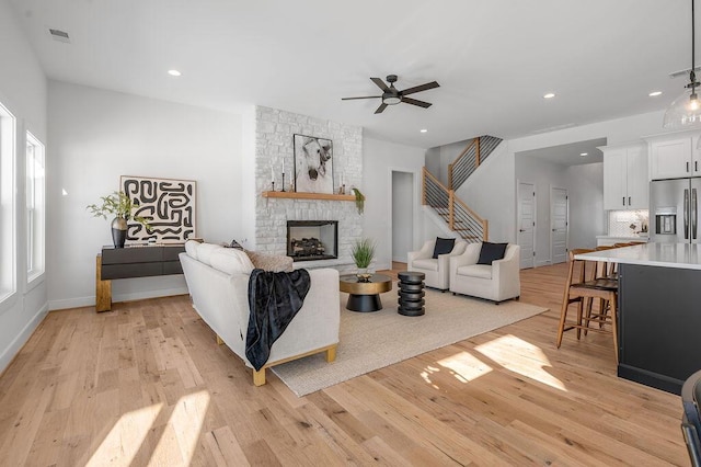 living room with a fireplace, light hardwood / wood-style floors, and ceiling fan