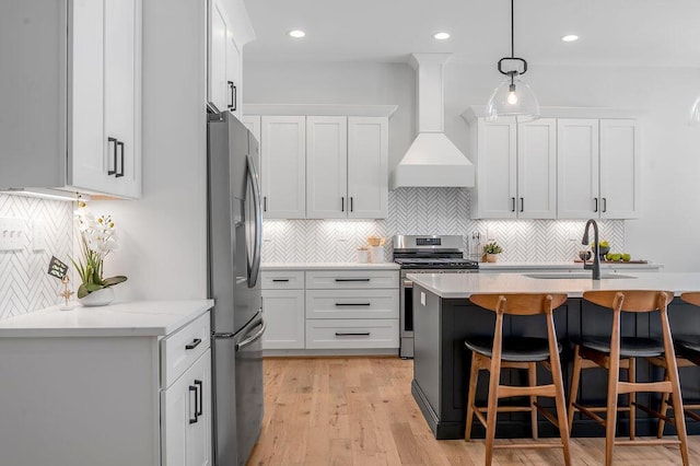 kitchen with custom range hood, stainless steel appliances, white cabinets, and sink