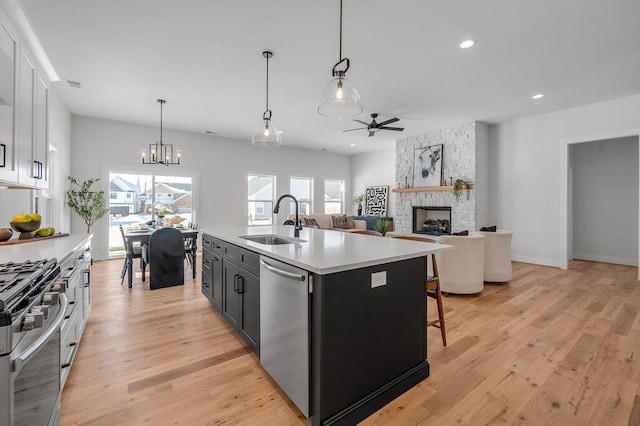 kitchen featuring white cabinetry, an island with sink, stainless steel appliances, decorative light fixtures, and sink