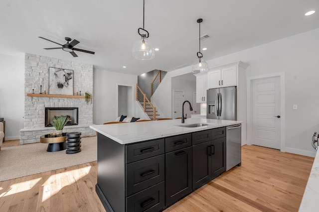 kitchen with an island with sink, ceiling fan, appliances with stainless steel finishes, white cabinets, and sink