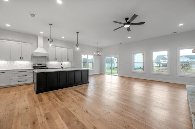 kitchen with pendant lighting, custom exhaust hood, white cabinetry, an island with sink, and stainless steel electric stove