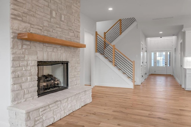 unfurnished living room with light hardwood / wood-style floors, a fireplace, and french doors