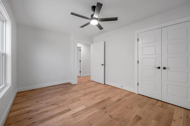 unfurnished bedroom featuring light wood-type flooring, ceiling fan, and a closet