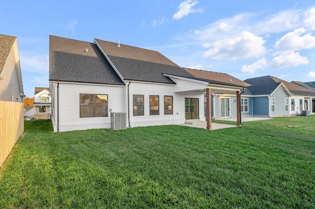 rear view of property with central air condition unit, a lawn, and a patio