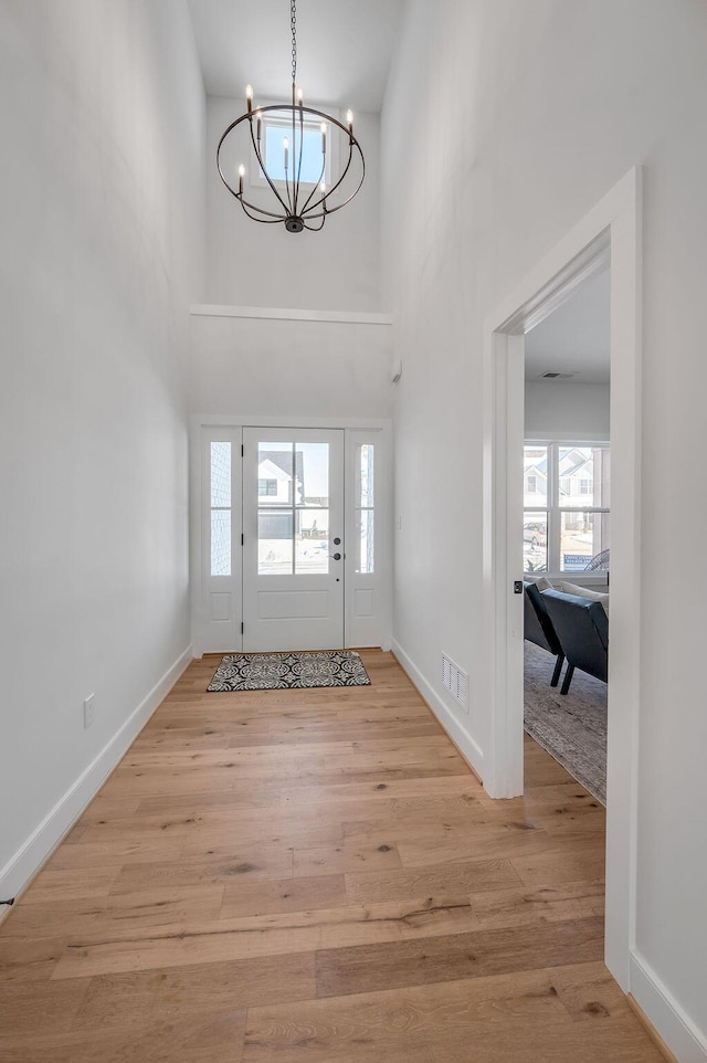 foyer featuring a high ceiling, an inviting chandelier, and light wood-type flooring