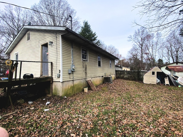 view of side of home featuring central AC unit and a shed