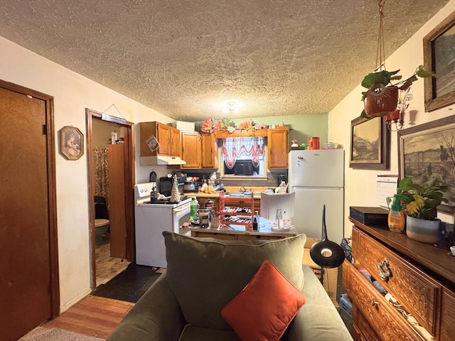 kitchen with a textured ceiling, wood-type flooring, and white appliances