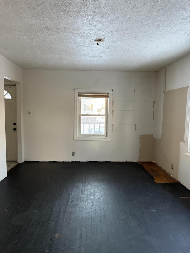 empty room featuring a textured ceiling and dark hardwood / wood-style flooring