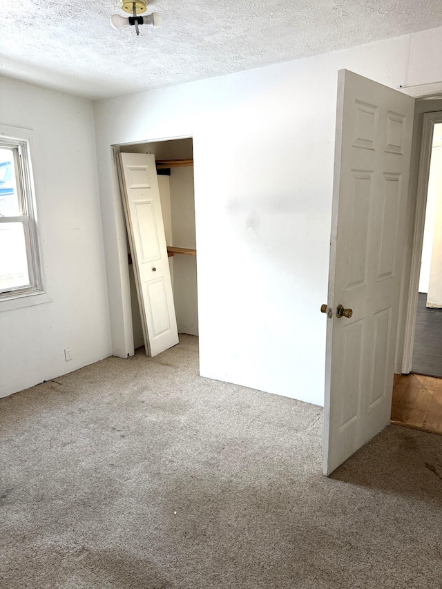 unfurnished bedroom featuring light colored carpet and a textured ceiling