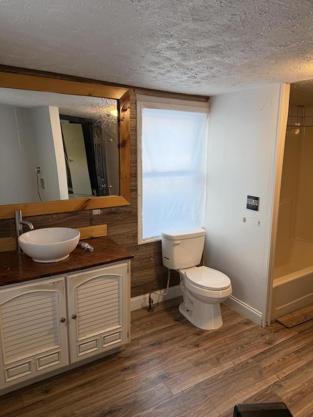 full bathroom with toilet, hardwood / wood-style floors,  shower combination, a textured ceiling, and vanity