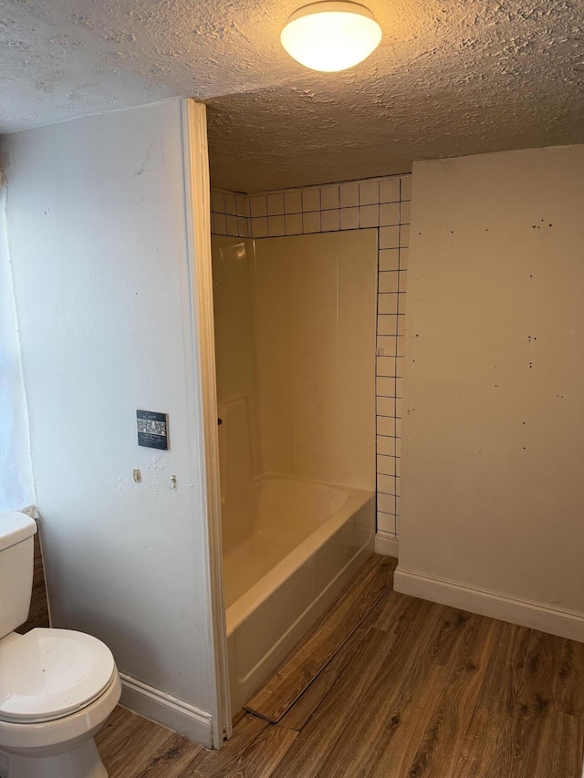 bathroom featuring wood-type flooring, toilet, and a textured ceiling