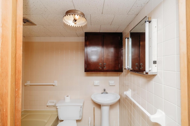 bathroom featuring toilet and tile walls