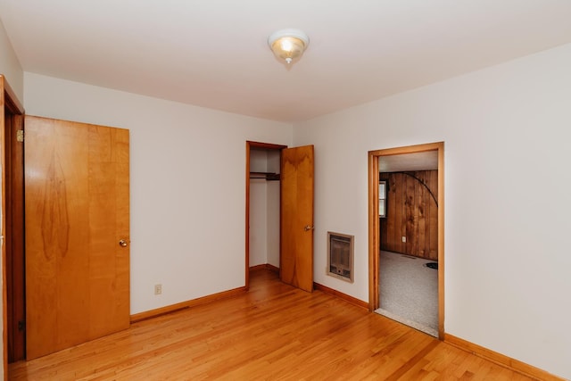 unfurnished bedroom featuring a closet, heating unit, and light hardwood / wood-style flooring