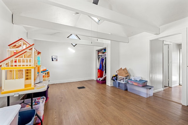 recreation room featuring wood-type flooring and vaulted ceiling with beams