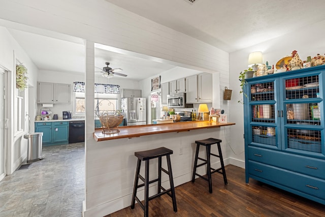 kitchen featuring a kitchen bar, butcher block countertops, appliances with stainless steel finishes, and kitchen peninsula