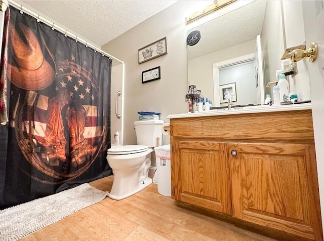 bathroom with wood-type flooring, toilet, vanity, and a textured ceiling