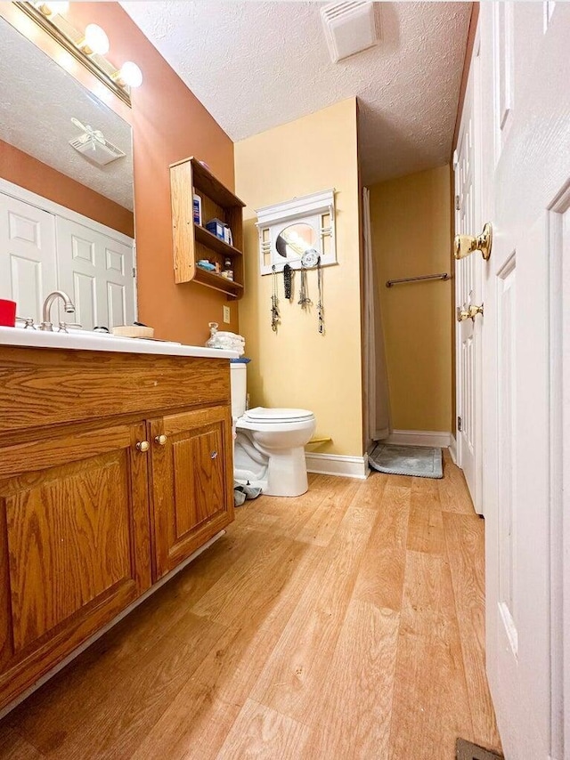 bathroom featuring a textured ceiling, toilet, hardwood / wood-style flooring, and vanity