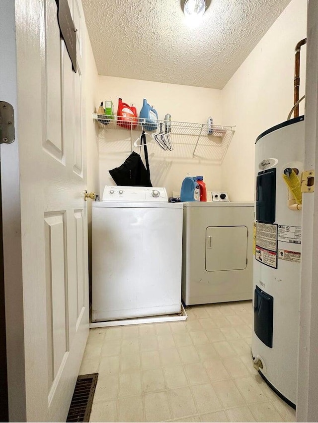 laundry area with a textured ceiling, washing machine and dryer, and water heater