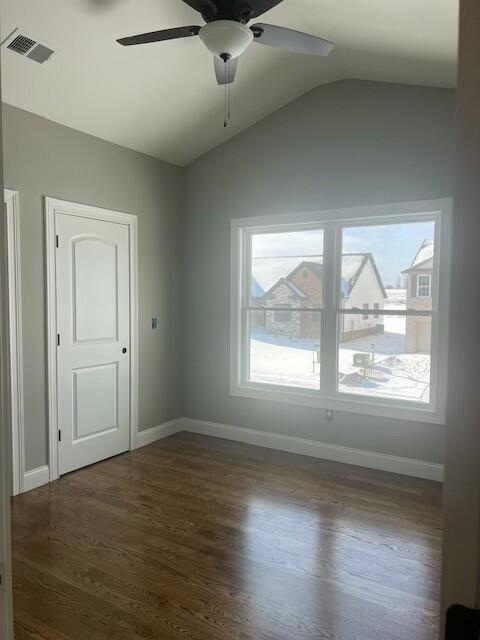 empty room with ceiling fan, plenty of natural light, dark hardwood / wood-style flooring, and lofted ceiling