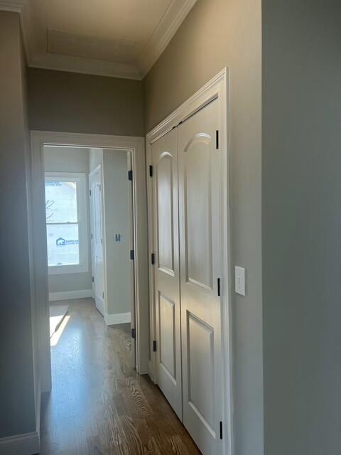 corridor with ornamental molding and hardwood / wood-style flooring