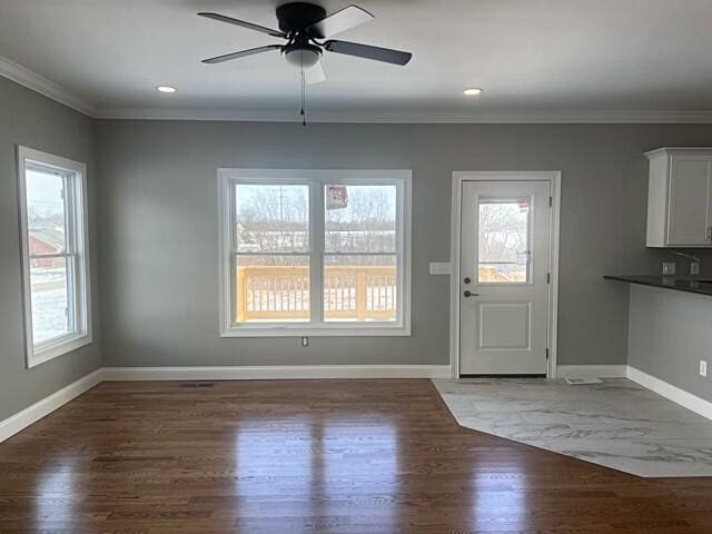 entryway with dark wood-type flooring, crown molding, and ceiling fan