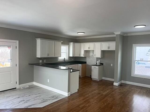 kitchen featuring decorative backsplash, white cabinets, and ornamental molding