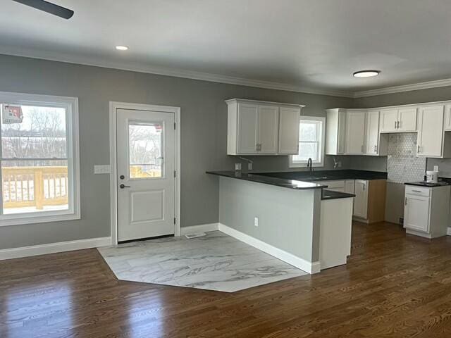 kitchen with backsplash, white cabinetry, dark hardwood / wood-style floors, and kitchen peninsula