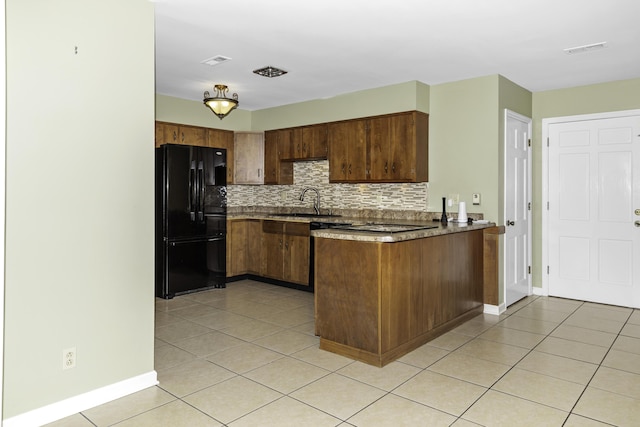 kitchen featuring backsplash, black fridge, kitchen peninsula, sink, and light tile patterned floors