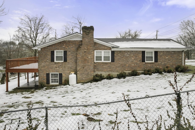 snow covered back of property with a deck