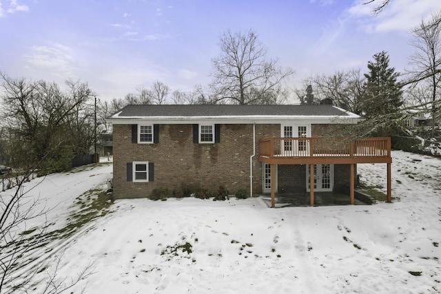 snow covered rear of property featuring french doors and a deck