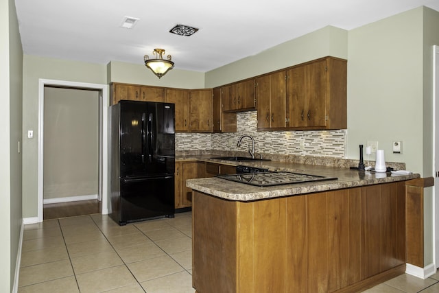 kitchen with light tile patterned floors, kitchen peninsula, tasteful backsplash, black appliances, and sink