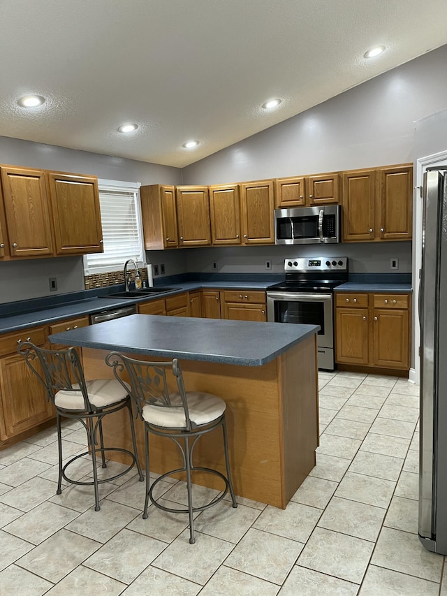 kitchen featuring a center island, vaulted ceiling, a breakfast bar area, and appliances with stainless steel finishes