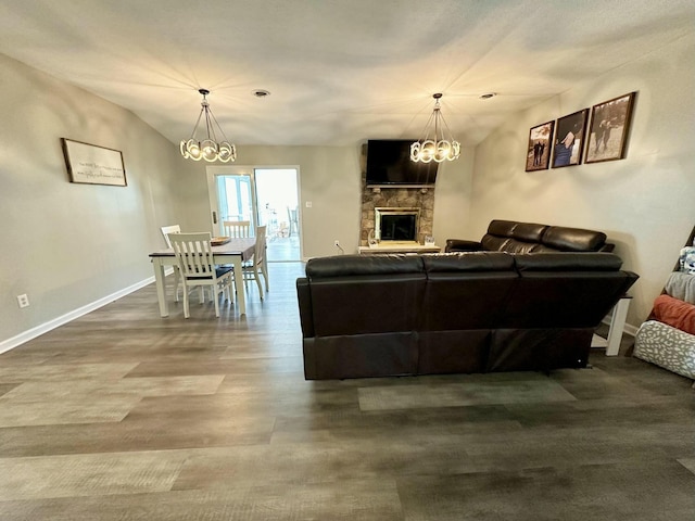 living room featuring an inviting chandelier, lofted ceiling, a fireplace, and hardwood / wood-style flooring