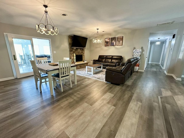 dining room with an inviting chandelier, a fireplace, and wood-type flooring