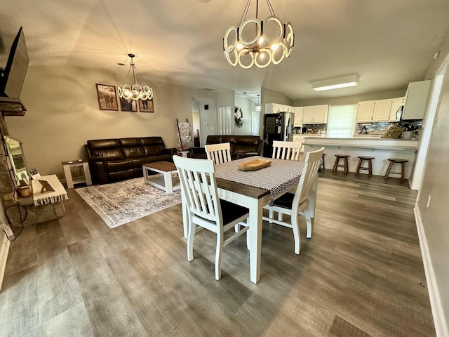 dining room with vaulted ceiling, a notable chandelier, and hardwood / wood-style floors