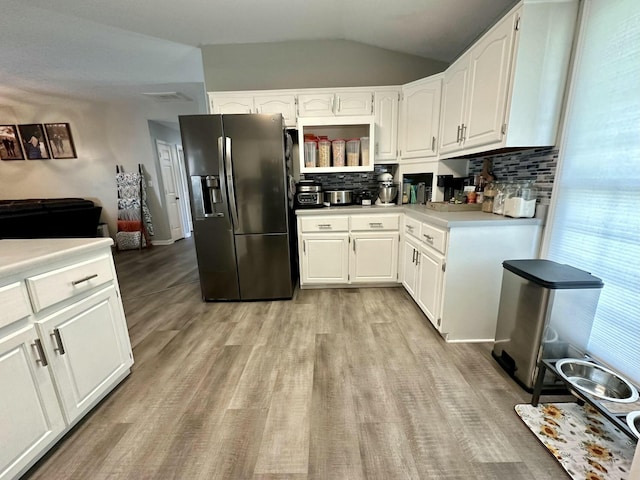 kitchen with stainless steel refrigerator with ice dispenser, white cabinetry, and tasteful backsplash